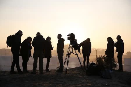 Journalists work in the camp called the "Jungle" in Calais on the second day of the evacuation of migrants and their transfer to reception centers in France, as part of the dismantlement of the camp in Calais, France, October 25, 2016. REUTERS/Neil Hall