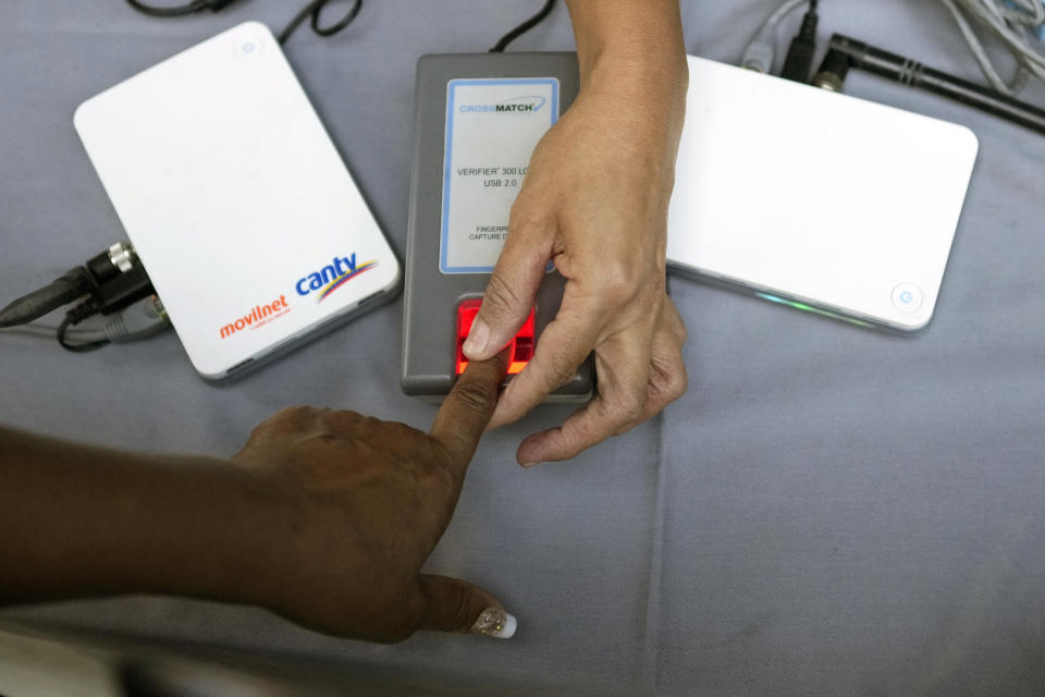 A person gives their fingerprint at a table set up by the National Election Council (CNE) where people can sign a petition in favor of holding a referendum to remove President Nicolas Maduro from office in Caracas, Venezuela, Wednesday, Jan. 26, 2022. The signatures of 20 percent of registered voter must be collected within 12 hours to request a presidential recall, a CNE rule that Maduro's opposition criticizes as impossible. (AP Photo/Matias Delacroix)