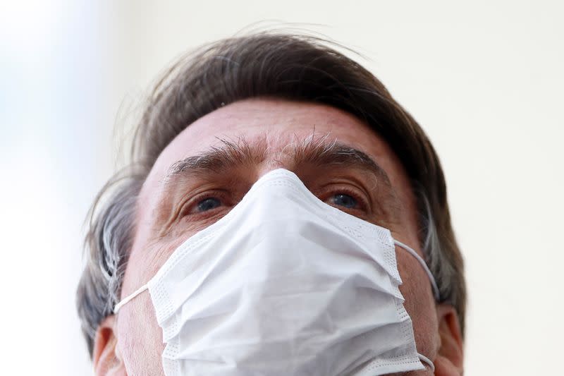 Brazil's President Jair Bolsonaro wearing a protective mask speaks with journalists, amid the coronavirus disease (COVID-19) outbreak, at the Planalto Palace, in Brasilia