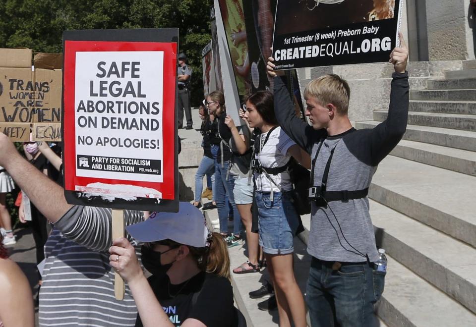 Anti-abortion activists stand on the steps of the Statehouse during a Women’s March held at the Ohio State Capitol in Columbus, Ohio, on Saturday, Oct. 2, 2021, in response to a Texas law that would ban abortion.