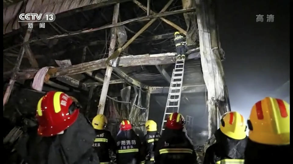 In this image taken from video footage run by China's CCTV, rescuers use a ladder to climb into the remains of a fire at an industrial wholesaler in Anyang in central China's Henan province, Monday, Nov. 21, 2022. A fire has killed several dozen people at a company dealing in chemicals and other industrial goods in central China's Henan province. (CCTV via AP)