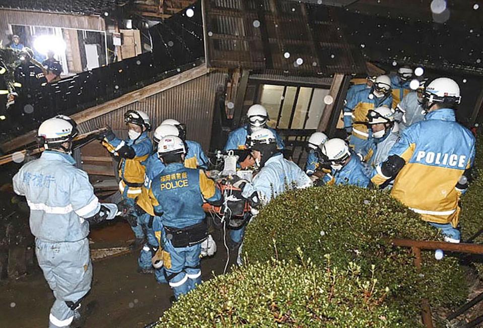 Police officers rescue a woman in her 90s from a collapsed house in Suzu, Ishikawa prefecture, Japan, on Saturday (AP)