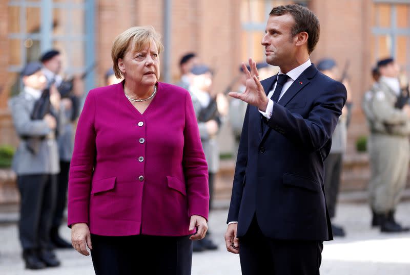 FILE PHOTO: French President Emmanuel Macron welcomes German Chancellor Angela Merkel before a joint Franco-German cabinet meeting in Toulouse