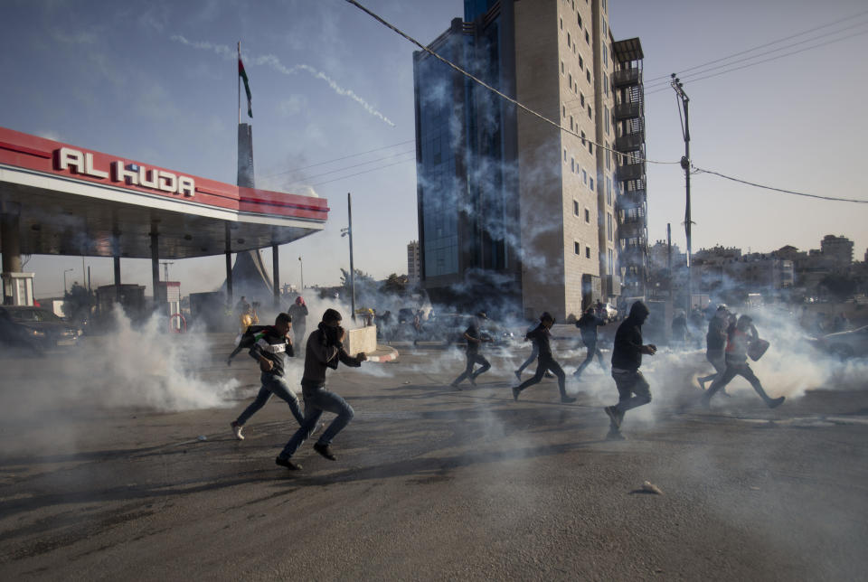 Palestinian demonstrators run from tear gas fired by Israeli troops during the protest against the U.S. announcement that it no longer believes Israeli settlements violate international law., at checkpoint Beit El near the West Bank city of Ramallah, Tuesday, Nov. 26, 2019, (AP Photo/Majdi Mohammed)