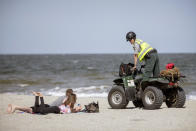 Georgia Department of Natural Resources Law Enforcement Division Corporal Barry Britt, right, enforces Gov. Bryan Kemp's order to open the beaches on Tybee Island, Ga., Saturday, April 4, 2020, allowing people to exercise outside, with social distancing of at least six feet because of the coronavirus outbreak. (Stephen B. Morton/Atlanta Journal-Constitution via AP)