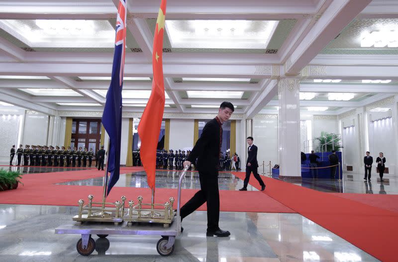 An attendant moves flags of New Zealand and China after a welcome ceremony in Beijing