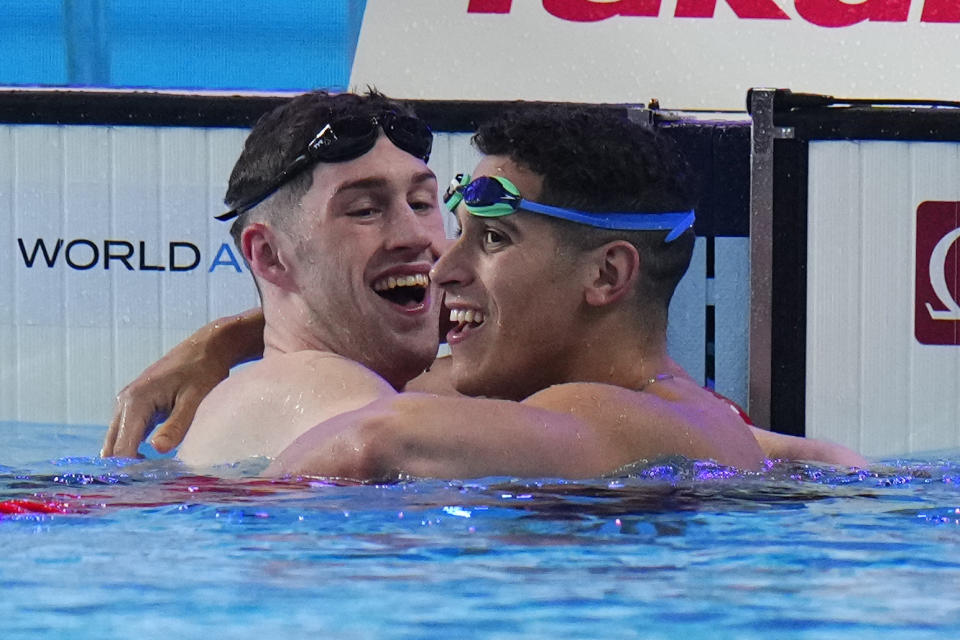 Hunter Armstrong of the United States, left, gold medal celebrates with Hugo Gonzalez of Spain, silver medal after the men's 100-meter backstroke final at the World Aquatics Championships in Doha, Qatar, Tuesday, Feb. 13, 2024. (AP Photo/Hassan Ammar)