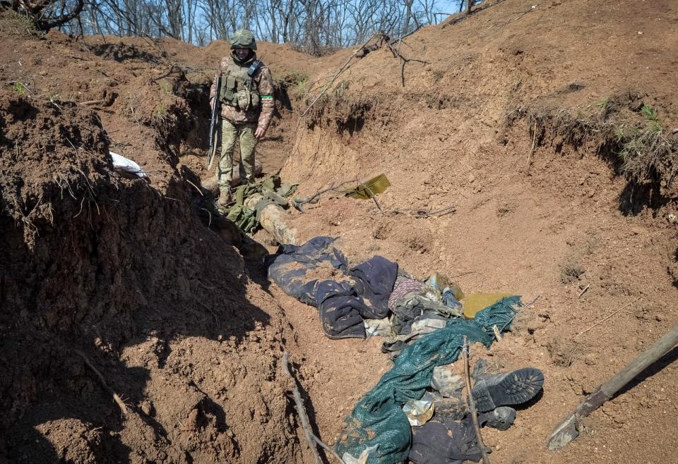 2023年4月10日，烏克蘭巴赫姆特（Bakhmut）前線，一名烏軍看著戰壕裡的俄軍遺體。路透社