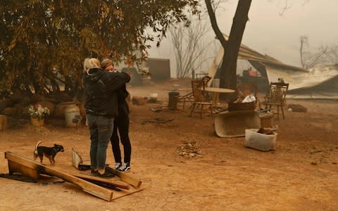 Krystin Harvey, left, comforts her daughter Araya Cipollini at the remains of their home in Paradise, Calif. - Credit: AP