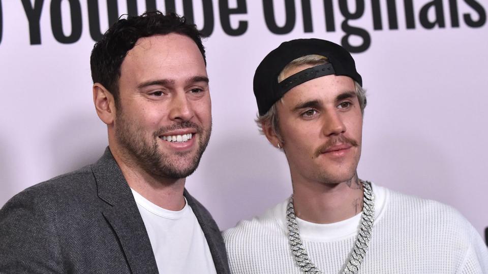 scooter braun embracing justin bieber with his left arm in a photo