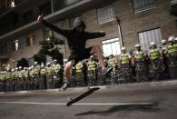 A demonstrator whose face is obscured by a handkerchief performs with his skateboard in front of military policemen during a protest against the 2014 World Cup in Sao Paulo March 27, 2014. REUTERS/Nacho Doce (BRAZIL - Tags: SPORT SOCCER WORLD CUP CIVIL UNREST TPX IMAGES OF THE DAY)