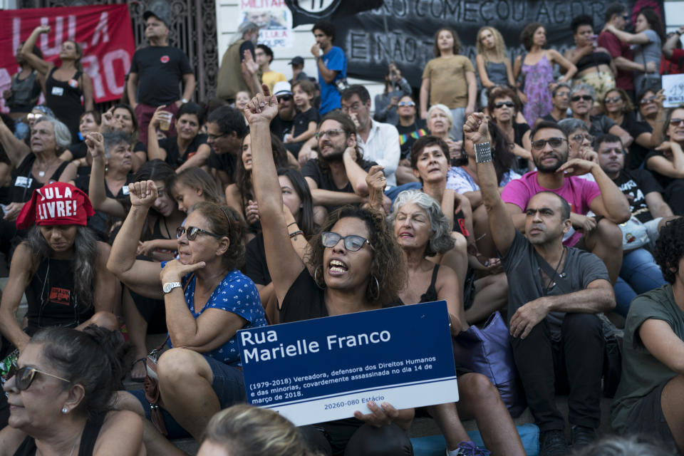 A woman holds a street sign honoring slain councilwoman Marielle Franco during a protest against the military coup of 1964 in Rio de Janeiro, Brazil, Sunday, March 31, 2019. Brazil's president Jair Bolsonaro, a former army captain who waxes nostalgic for the 1964-1985 dictatorship, asked Brazil's Defense Ministry to organize "due commemorations" on March 31, the day historians say marks the coup that began the dictatorship. (AP Photo/Leo Correa)