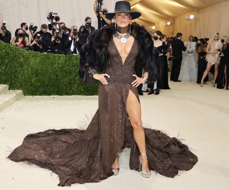 <p>Mike Coppola/Getty Images</p><p>Jennifer Lopez channeled a high-couture <em><a href="https://parade.com/tag/yellowstone" rel="nofollow noopener" target="_blank" data-ylk="slk:Yellowstone;elm:context_link;itc:0;sec:content-canvas" class="link ">Yellowstone</a> </em>vibe for the <a href="https://parade.com/1261911/paulettecohn/met-gala-fashion-2021-red-carpet-photos/" rel="nofollow noopener" target="_blank" data-ylk="slk:2021 Met Gala;elm:context_link;itc:0;sec:content-canvas" class="link ">2021 Met Gala</a> theme, "In America: A Lexicon Of Fashion." Sporting a brown beaded and textured Ralph Lauren gown with a deep V-neck and high leg slit, accessorized with a black and brown fur jacket, silver plated necklace, leather choker and bracelets, silver earrings, silver heels and a black cowboy hat.</p>
