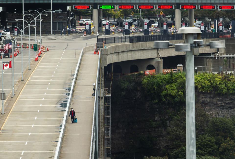 A person crosses the International Rainbow Bridge from Niagara Falls, N.Y. into Niagara Falls, Ontario, on Wednesday, Oct. 13, 2021. The U.S. will reopen its land borders to nonessential travel next month, ending a 19-month freeze due to the COVID-19 pandemic as the country moves to require all international visitors to be vaccinated against the coronavirus. The new rules, to be announced Wednesday, Oct. 13, 2021 will allow fully vaccinated foreign nationals to enter the U.S. regardless of the reason for travel. (Aaron Lynett/The Canadian Press via AP)