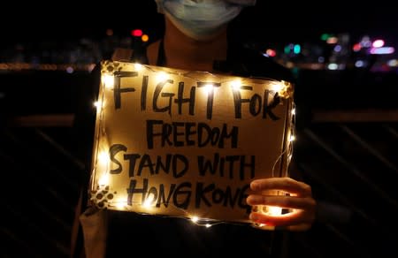 A woman holds a placard as protesters hold hands to form a human chain during a rally to call for political reforms at Tsim Sha Tsui and Hung Hom Promenade in Hong Kong