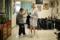 Pastoral Care Services Worker and inmate Kao Saephanh helps inmate Eddie Van Houton, 71, who has cancer, stand up after giving him a haircut in the hospice at the California Medical Facility prison in Vacaville, California, U.S., May 23, 2018. Saephanh, who is in prison for killing a man at a Halloween party in 2006 when he was 17, assists the medical staff with patient care such as changing diapers, showering or changing their sheets. He is also the hospice barber. "I knew that once I got here (to the hospice) I was going to be able to give back a little bit," Saephanh said. "The hardest part is seeing people that you care for pass away and then sometimes they pass away without their family here. So, we are the only means of support for them at the time." REUTERS/Lucy Nicholson