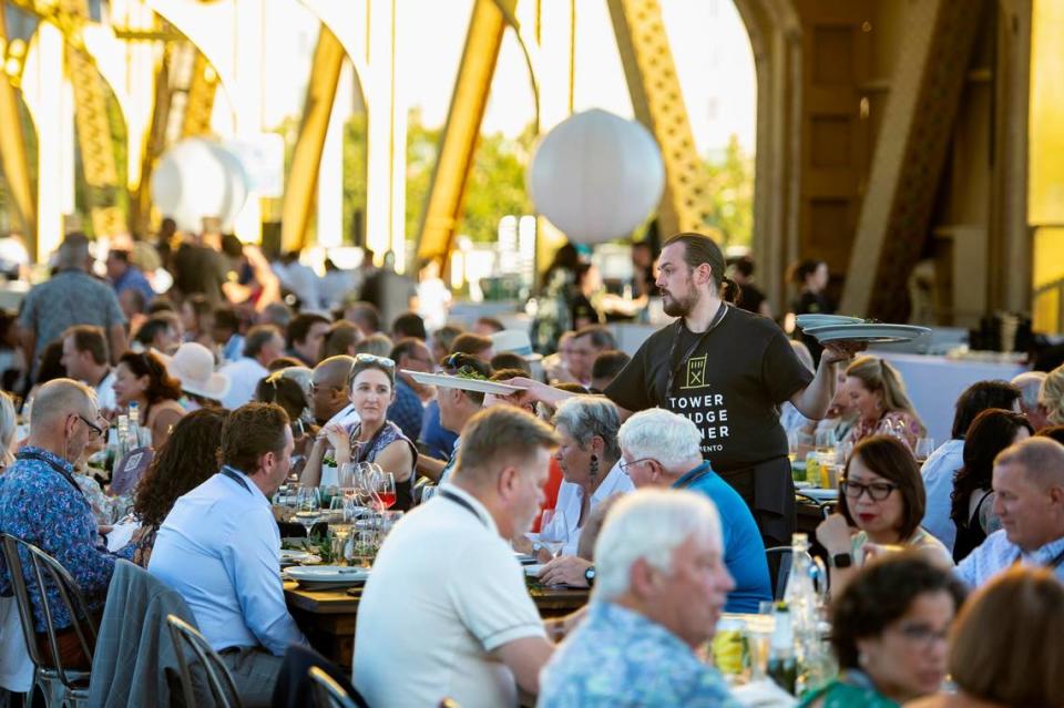 A server removes plates from the table at the Tower Bridge Dinner on the Tower Bridge between Sacramento and West Sacramento on Sunday.