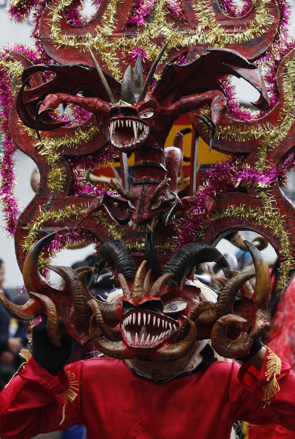 A man with a devil's mask dances in La Diablada in Pillaro, Ecuador, Monday, Jan. 6, 2014, to celebrate the end of the year and the start of the new one. The town of Pillaro kicks off the feast of La Diablada with neighborhoods competing to bring in as many people as possible dressed as different characters. Originally the devil costume was used to open up space to allow other participants to dance, but over the years the character gained popularity and became the soul of the feast. (AP Photo/Dolores Ochoa)