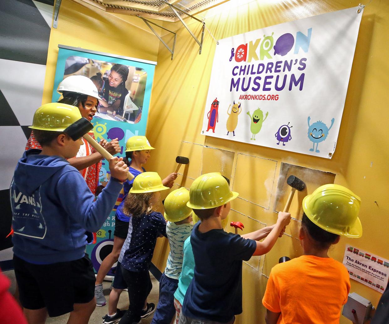 Akron Children's Museum Executive Director Traci Buckner, rear, gets help breaking down the first wall from museum goers to kick off the museum's $650,000 expansion project on Wednesday.
