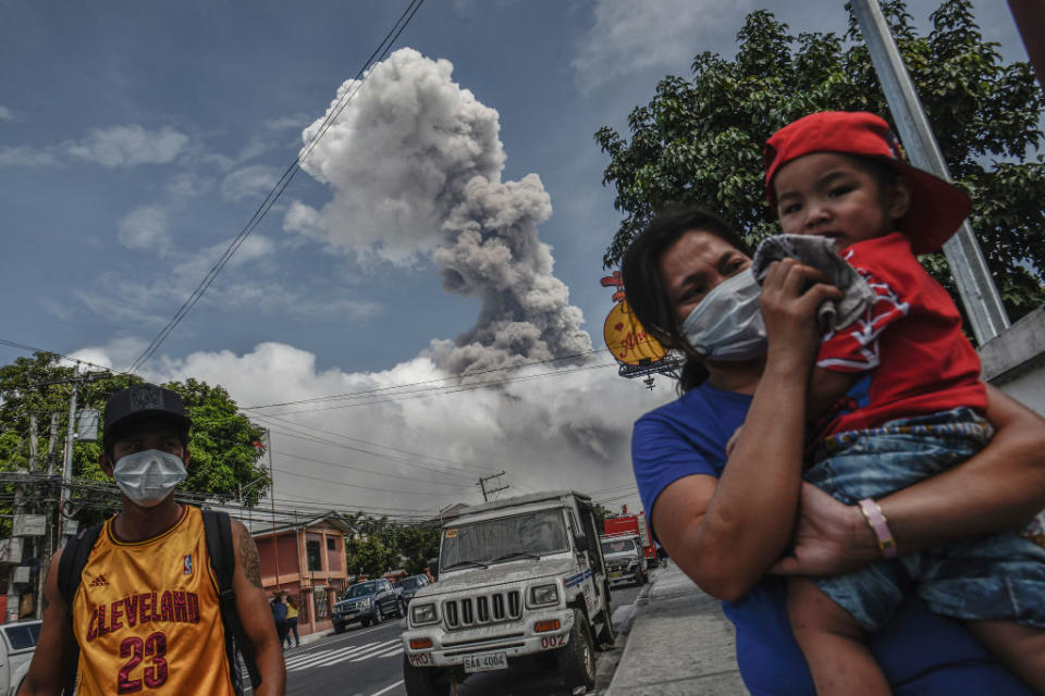 <p>A woman covers the face of a child as Mount Mayon spews a huge column of ash noon in Camalig, Albay province, Philippines. Mount Mayon, the Philipines’ most active volcano located in eastern Philippines, has been spewing fresh lava and ash for almost two weeks. More than 74,000 people have been evacuated in emergency shelters as authorities warn of a potentialy hazardous eruption that could take place in just days. (Ezra Acayan/NurPhoto via Getty Images) </p>