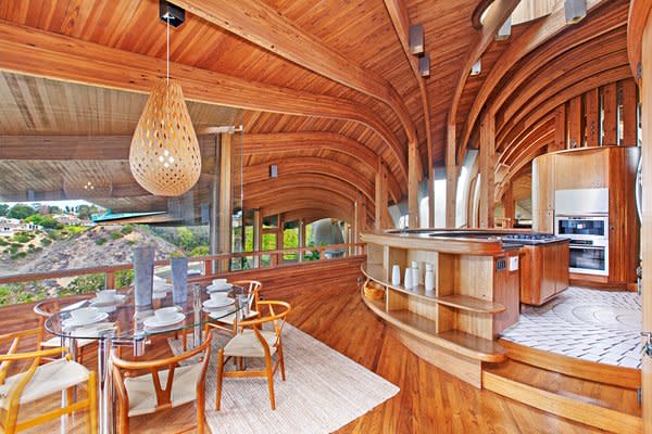 The curvilinear, individually treated Douglas Fir beams cascade out from the central atrium. This is a look at the kitchen which features built-in teak cabinetry and an original light fixture over the table.