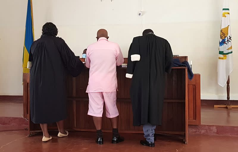 Paul Rusesabagina, portrayed as a hero in a Hollywood movie about Rwanda's 1994 genocide, stands with his lawyers inside the courtroom before answering to charges that include terrorism and incitement to murder in Kigali