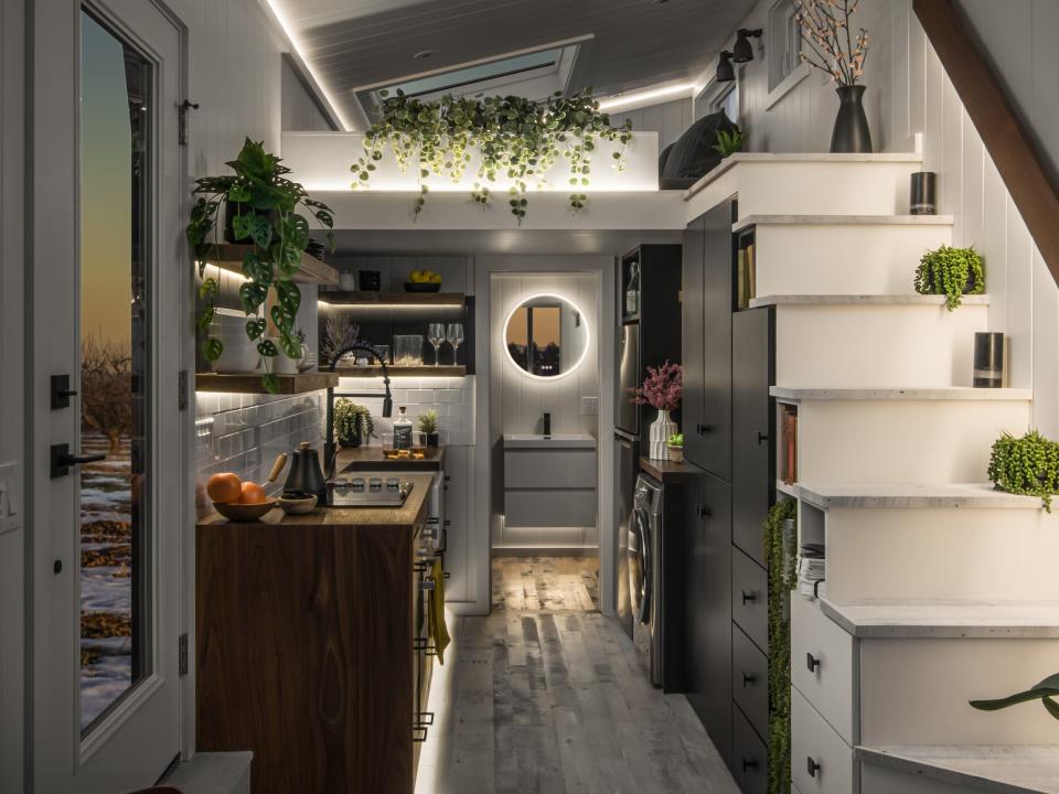 a dark tiny home's kitchen and staircast lit up with LED lights