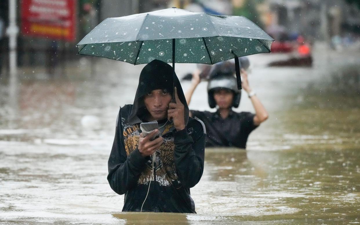 Man wades through flood waters - Girl drowns as tropical storm batters Philippines