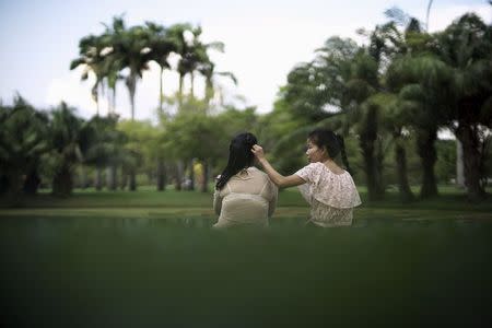 Aye Than Dar (R) touches the head of her sister Hla Thidar Myint (L) at a park in Bangkok, Thailand, November 14, 2015. REUTERS/Athit Perawongmetha