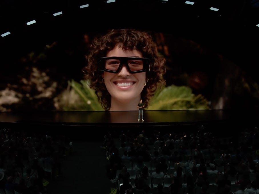 Woman wearing Snap Spectacles on stage backdrop