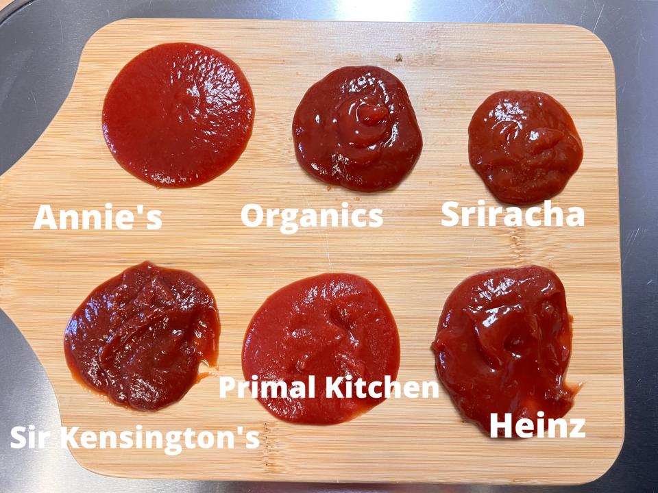 A lined up of samples of different ketchup brands on wooden cutting board