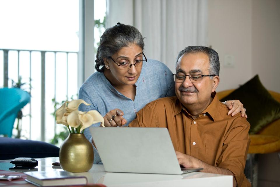 Two people behind a laptop, one looking over the other's shoulder.