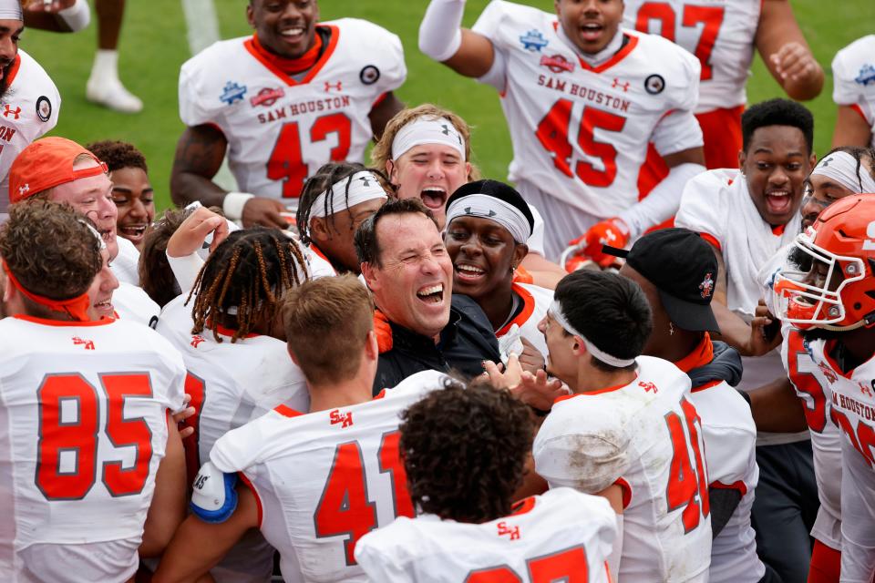 FILE - Sam Houston State head coach K.C. Keeler, center, is swarmed by his team after they defeated South Dakota State in the NCAA college FCS Football Championship in Frisco, Texas, in this Sunday May 16, 2021, file photo. Sam Houston State won 23-21. Keeler didn't ask his Sam Houston players to stick around long after they won the school's first FCS national championship last May, capping a long and draining season -- physically and emotionally -- because of the pandemic. He's also not asking them to stick around as long at practice this year. Throughout the Championship Subdivision, coaches are making concessions this fall to acknowledge that the quick turnaround from last spring is hard. (AP Photo/Michael Ainsworth, File)