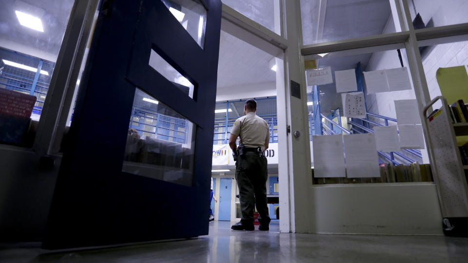 FILE - A Sheriff officer stands guard over inmates at the Twin Towers Correctional Facility Thursday, April 27, 2017, in Los Angeles. Jails across the U.S. are suffering from overcrowding, violence and abuse. It comes as staffing problems at lockups from New York to California continue to grow and have made long-simmering problems worse. (AP Photo/Chris Carlson, File)