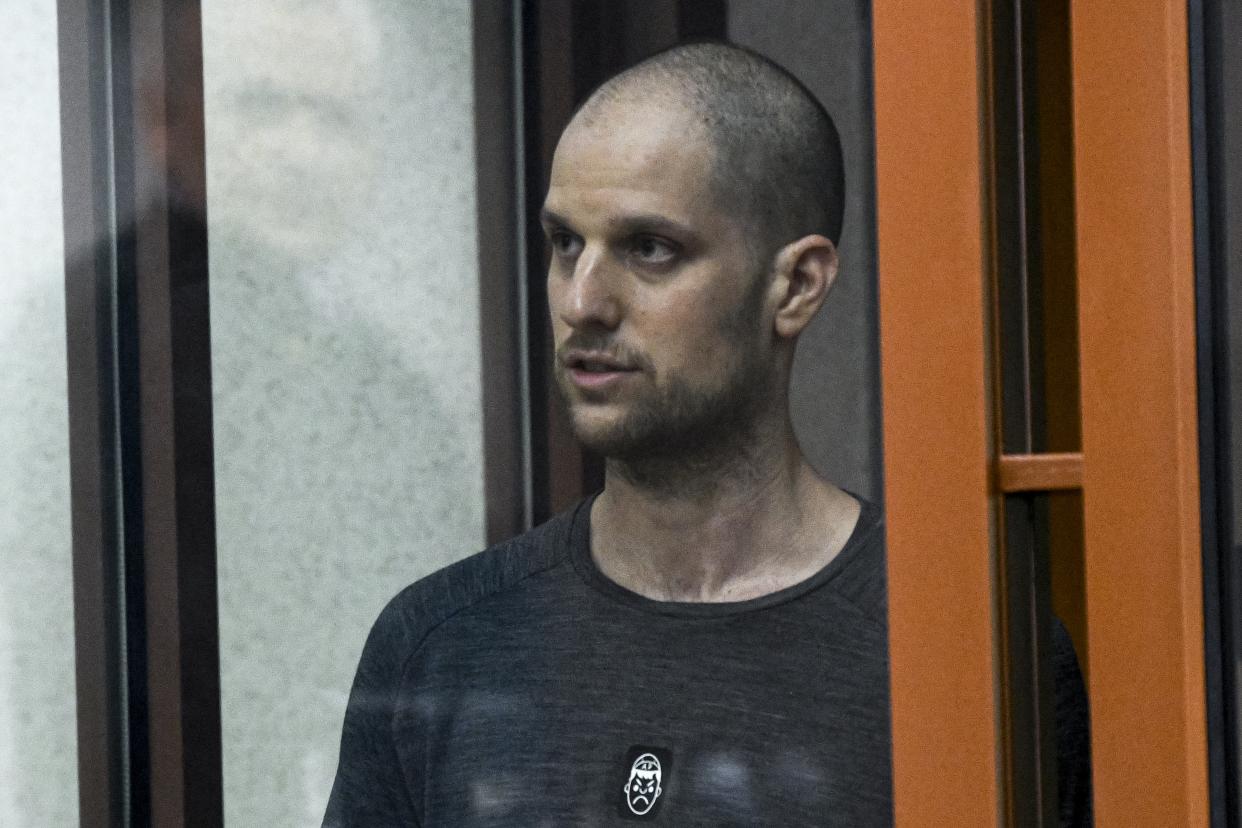 Wall Street Journal reporter Evan Gershkovich stands listening to the verdict in a glass cage of a courtroom inside the building of 