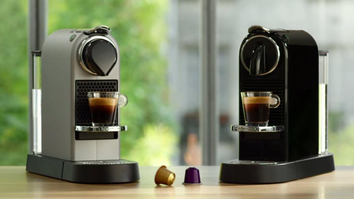  Two Nespresso Citiz espresso coffee maker machines on wooden worktop. 