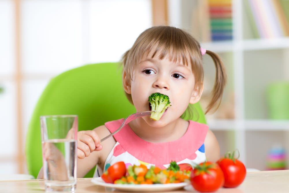 Girl feeding herself veggies