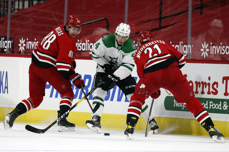 Dallas Stars' Joel Hanley (44) battles between Martin Necas (88) and Nino Niederreiter (21) during the first period of an NHL hockey game in Raleigh, N.C., Sunday, Jan. 31, 2021. (AP Photo/Karl B DeBlaker)