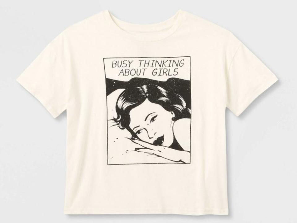 A cream shirt on a white background has a blocked photo of a woman's face. Above her, the text says "Busy thinking about girls."