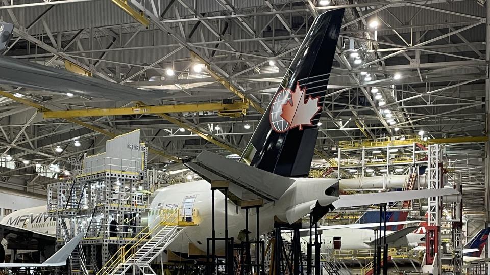 View inside a giant airplane hangar with structural work being done on the airframe.