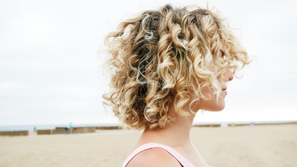 woman with curly hair side profile, on the beach