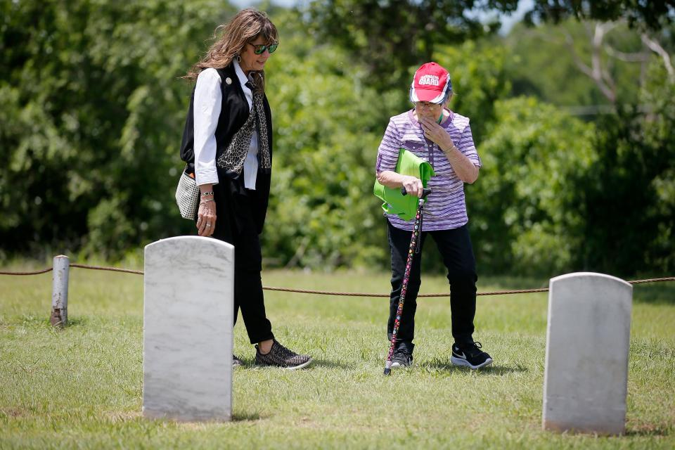 Brenda Wolfley, left, walks with Betty Hendricks, with Daily Living Centers, as they look at graves after placing flower arrangements on them Thursday at Veterans Cemetery in Oklahoma City.