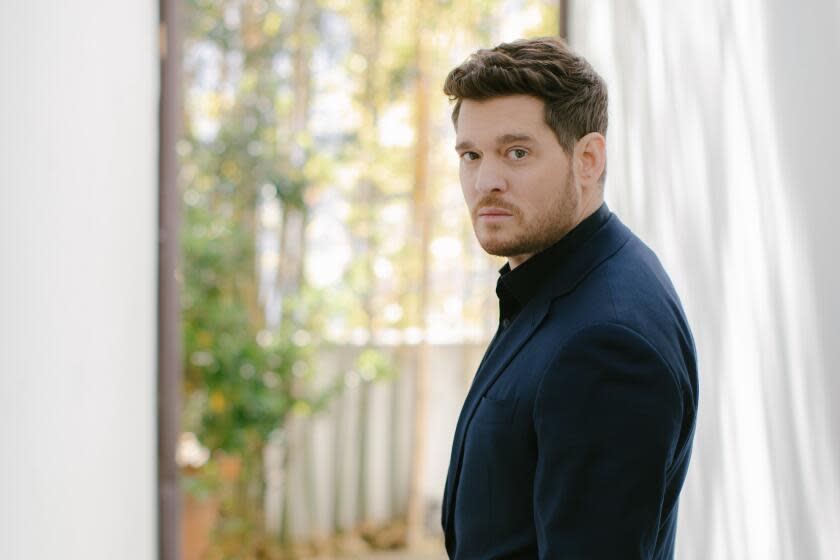 Side profile shot of Michael Bublé in a dark blue suit against a natural, outdoor background