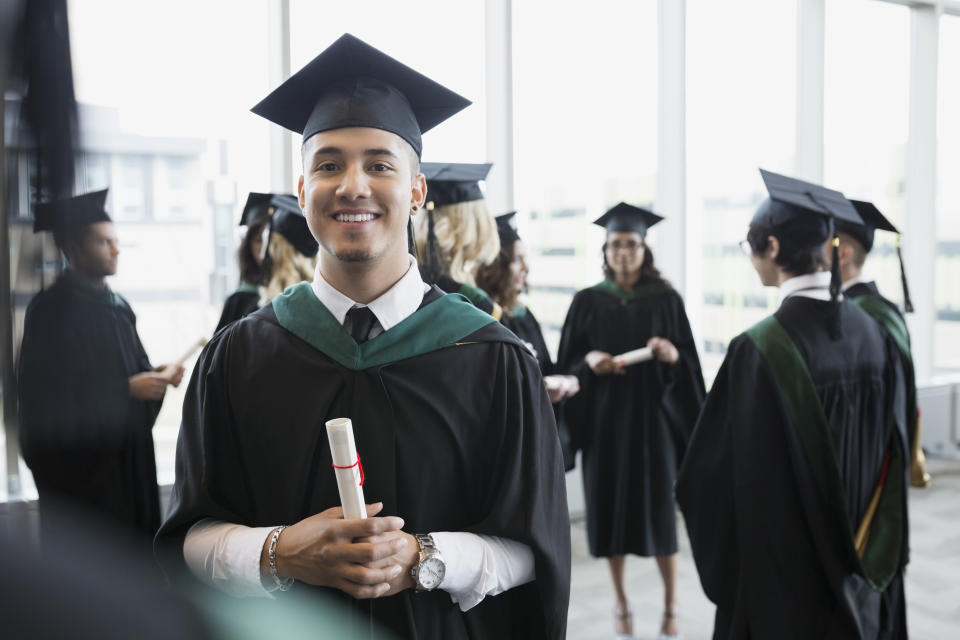 Portrait confident college graduate cap and gown diploma