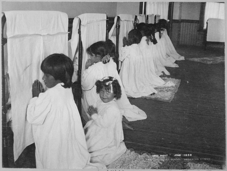 Little girls pray beside their beds at the Phoenix Indian School, June 1900.