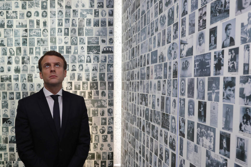 FILE - In this Sunday, April 30, 2017 file picture, independent centrist presidential candidate Emmanuel Macron looks at some of the 2,500 photographs of young Jews deported from France, during a visit to the Shoah memorial in Paris, France. France's prime minister is sounding the alarm over a sharp rise in anti-Semitic acts this year, pledging to increase efforts to punish perpetrators and police hate speech online.(Philippe Wojazer/Pool Photo via AP, File)