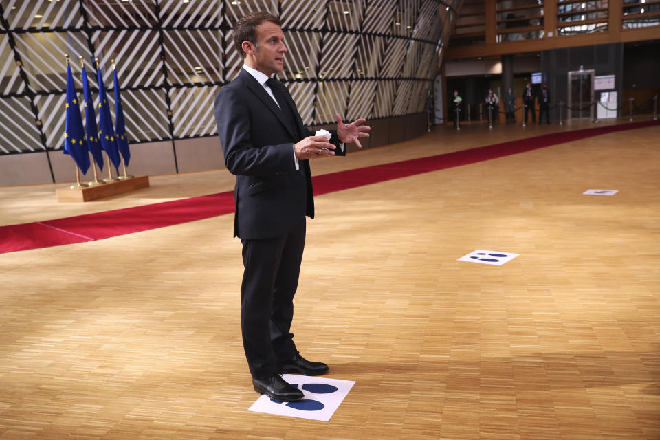 French President Emmanuel Macron makes a statement to the media as he stands on a physical distancing marker on arrival for an EU summit in Brussels, Sunday, July 19, 2020. Leaders from 27 European Union nations meet face-to-face for a third day to assess an overall budget and recovery package spread over seven years estimated at some 1.75 trillion to 1.85 trillion euros. (AP Photo/Francisco Seco, Pool)