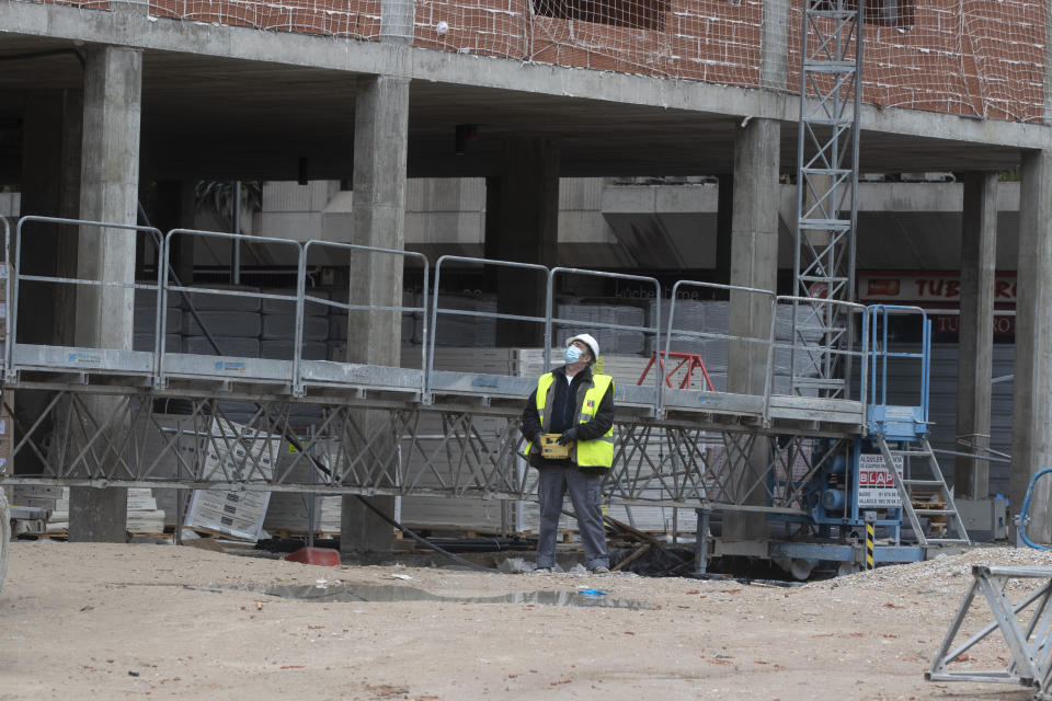 A construction worker operates a crane by remote control at a building site in Madrid, Spain, Monday, April 13, 2020. Heavy industry and construction workers are returning to work from Monday after a two-week hiatus in economic activity due to the coronavirus restrictions but the government is keeping most Spaniards under confinement for the fifth week in a row.The new COVID-19 coronavirus causes mild or moderate symptoms for most people, but for some, especially older adults and people with existing health problems, it can cause more severe illness or death. (AP Photo/Paul White)