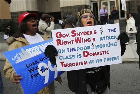 Resident Renla Session (R) holds a sign as she protests against Michigan Governor Rick Snyder's polices in front of the Federal Court House in Detroit, Michigan October 28, 2013. REUTERS/Rebecca Cook