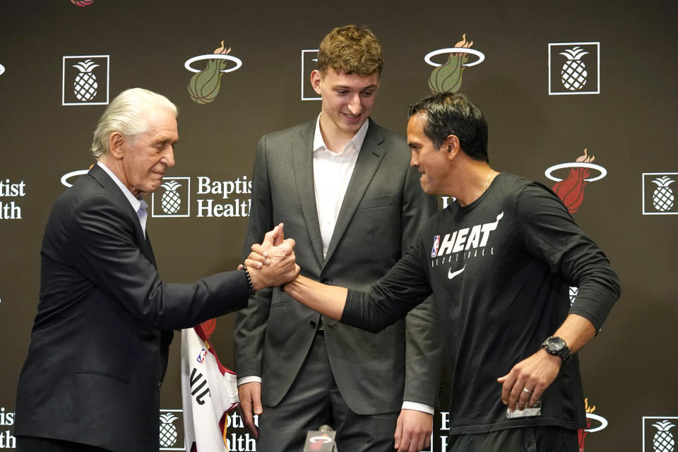 Miami Heat president Pat Riley, left, shakes hands with head coach Erik Spoelstra, right, as Nikola Jovic, of Serbia, center, looks on during a news conference, Monday, June 27, 2022, in Miami. Jovic was selected by the Miami Heat as the No. 27 pick in the 2022 NBA draft. (AP Photo/Lynne Sladky)